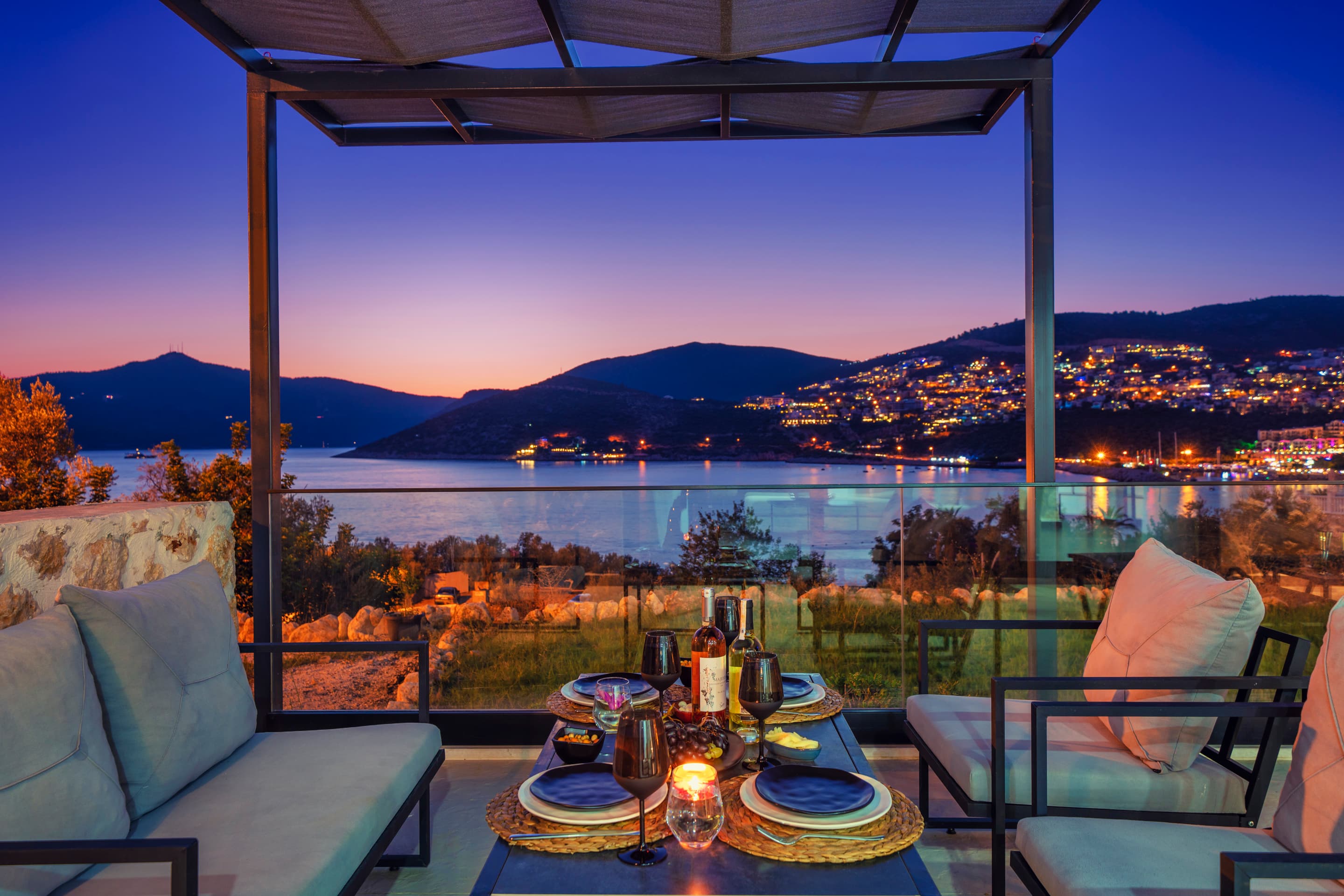 A table set for the evening on a Kalkan villa terrace, with the illuminated bay in the background