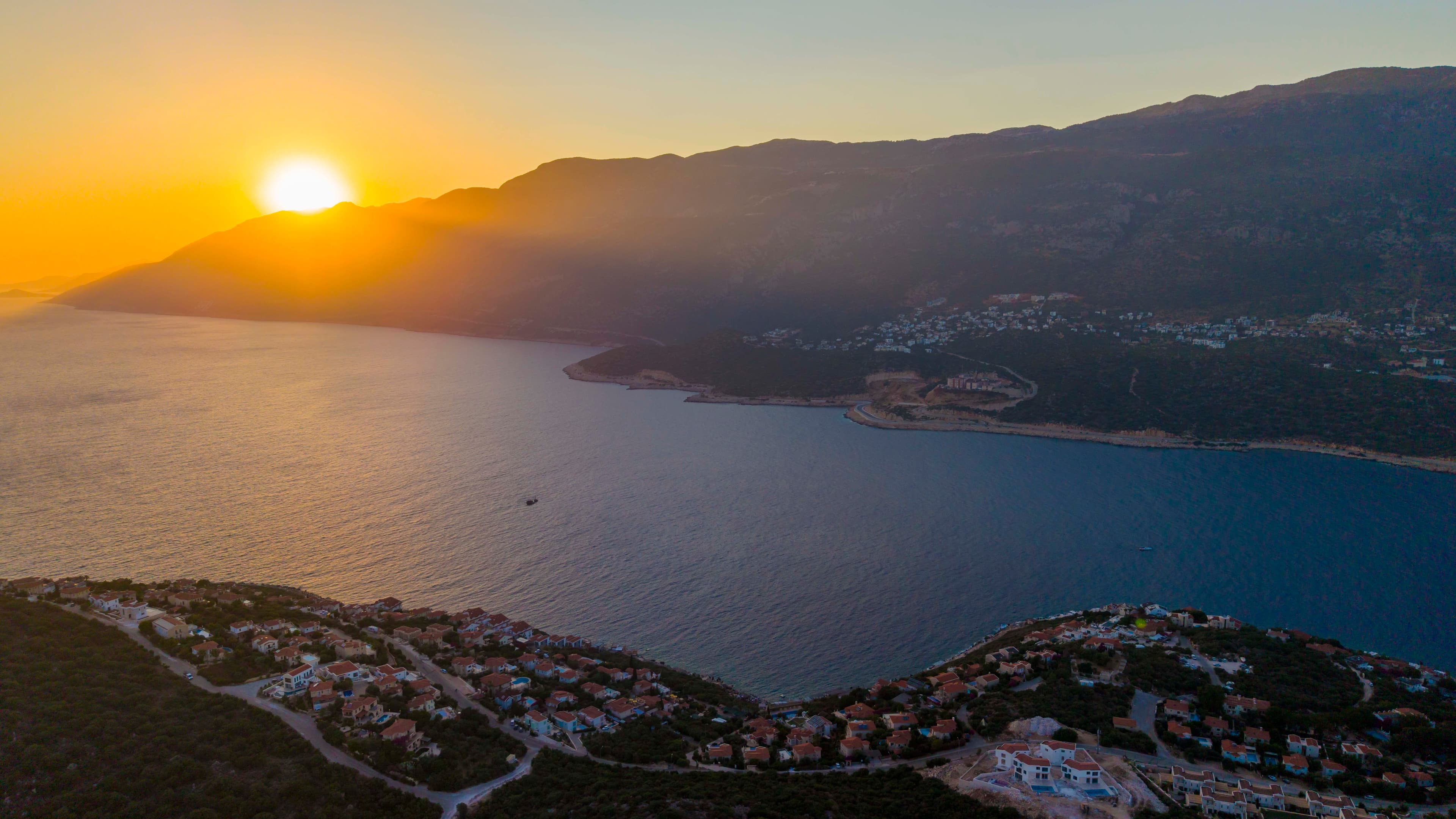 An aerial view of the Kaş peninsula at sunset, with the town nestled along the bay