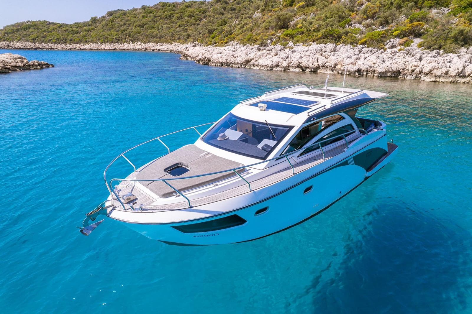 A private motor yacht anchored in a clear turquoise cove along the coast