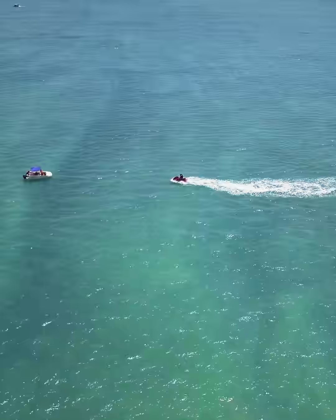 A jet ski drawing a wake across open water, from the air